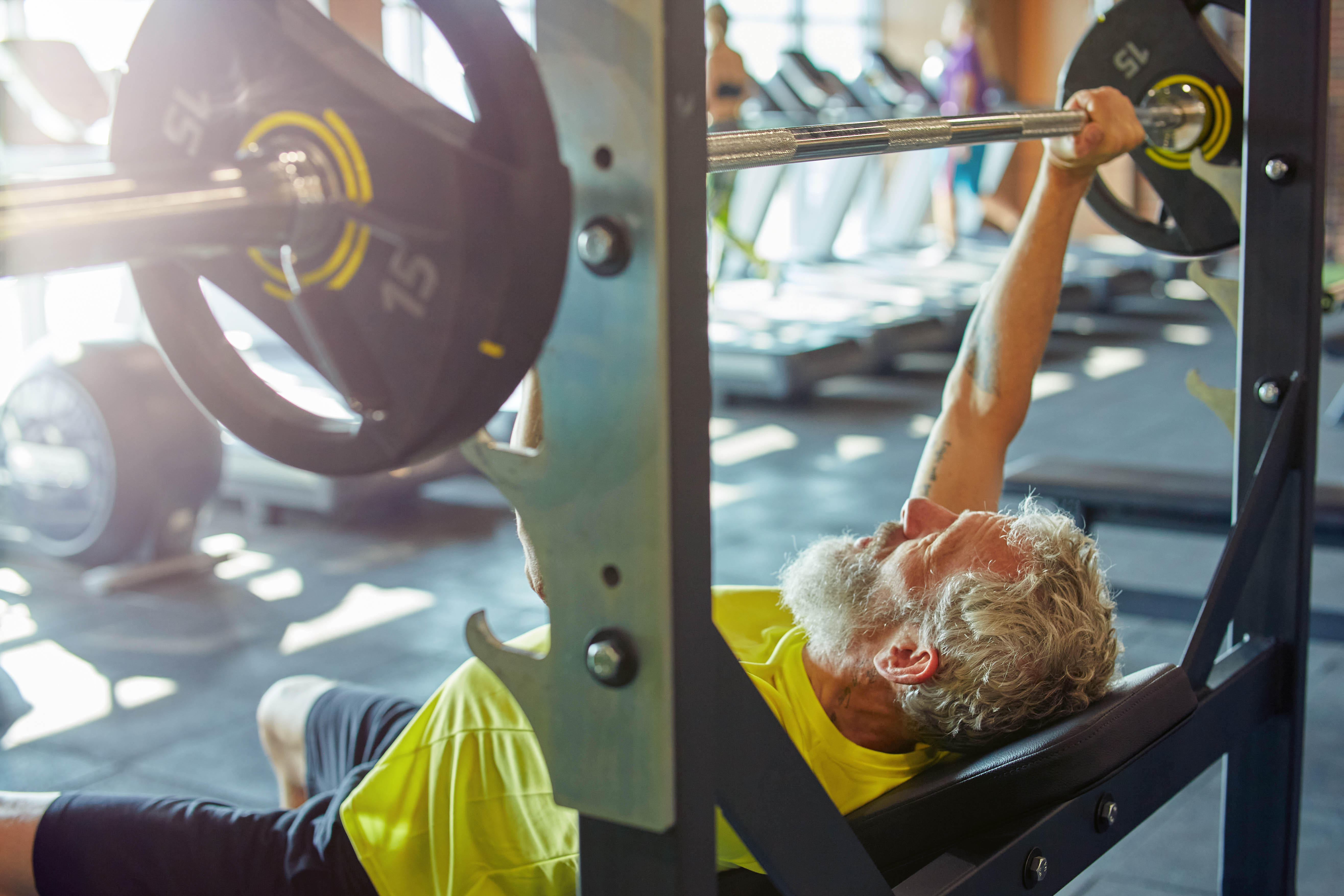 Older man doing a bench press in the gym